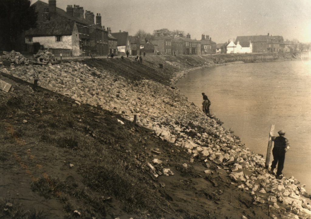 Workmen undertaking riverting work along the river Trent